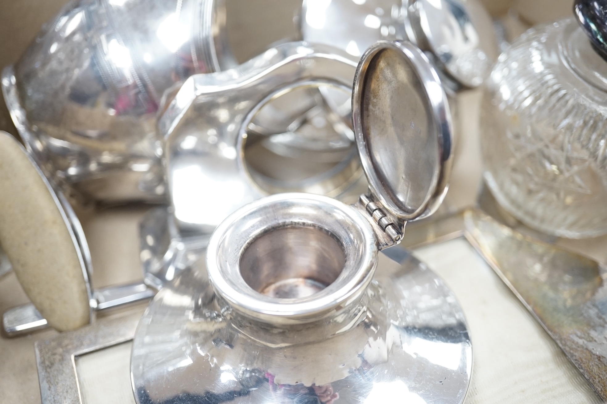 A quantity of assorted small silver including a George III cream jug(a.f.), three small capstan inkwells, a watch stand, photograph frame, mounted glass toilet jars etc. Condition - poor to fair